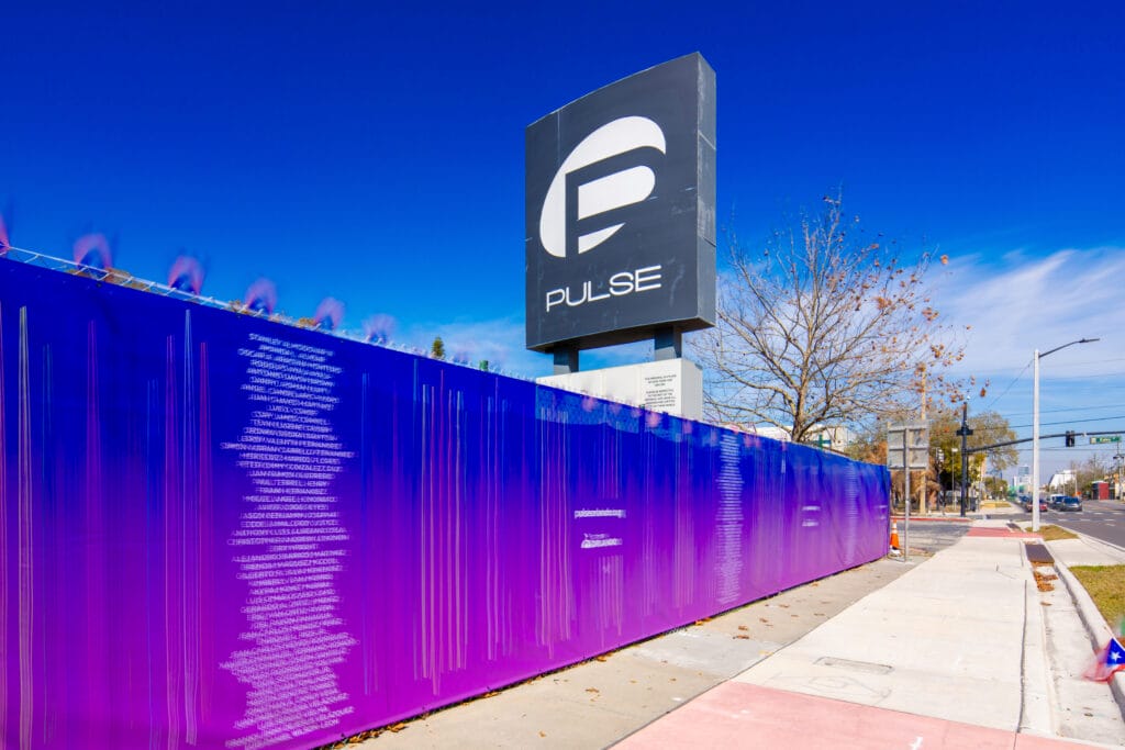 Pulse Nightclub sign in Orlando above purple memorial walls listing victims’ names, marking the site of the 2016 mass shooting.