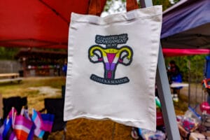 Canvas tote bag with feminist political artwork displayed at a Lezapalooza vendor booth.